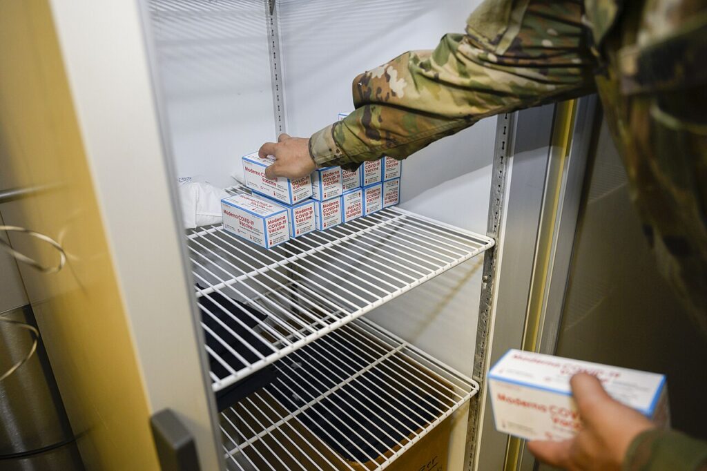 Medical staff handling refrigerated vaccine stock in a temperature-controlled store